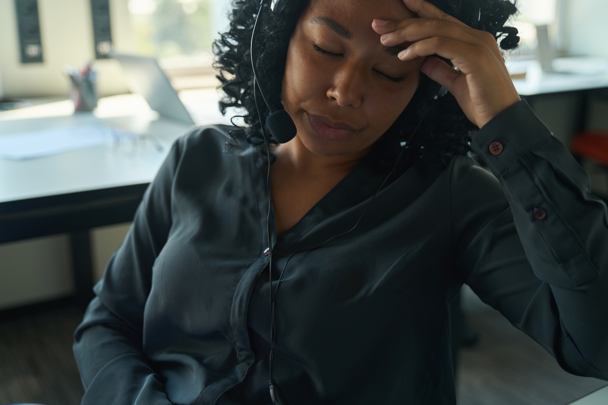 A professional at her desk, headset on, carrying the weight of the day
